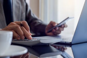 Business man hand using mobile smart phone and calculator